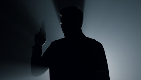 silhouette gunner raising hand with pistol in darkness. criminal holding gun.