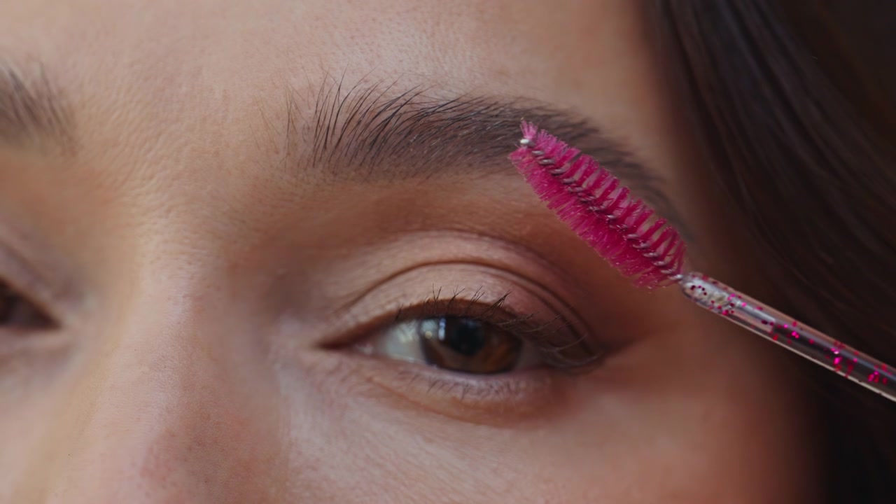 Beautiful woman brushing eyebrows with cosmetic spoolie home closeup. Young lady