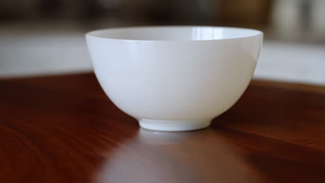 hand reaching for a white bowl on a wooden table