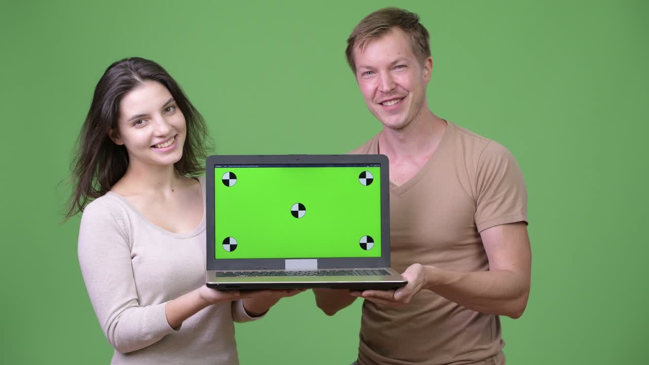 Young happy couple smiling while showing laptop together