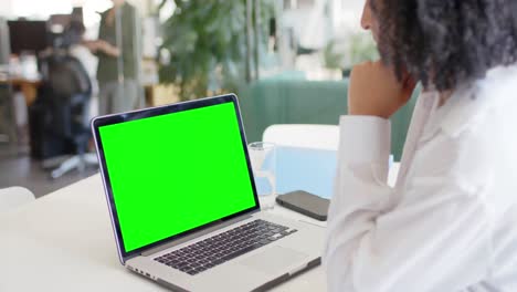 Mujer-De-Negocios-Birracial-Viendo-Laptop-Con-Pantalla-Verde-En-La-Oficina,-Cámara-Lenta