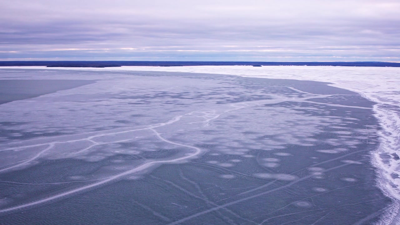 Aerial footage of frozen Great Lakes surface with cracked and layered ice formations