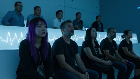 captivated audience: a group of individuals engaged in an immersive experience within a minimalist space featuring continuous visual elements and emotional engagement