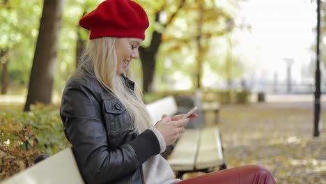 Happy-looking-woman-in-beret-using-smartphone