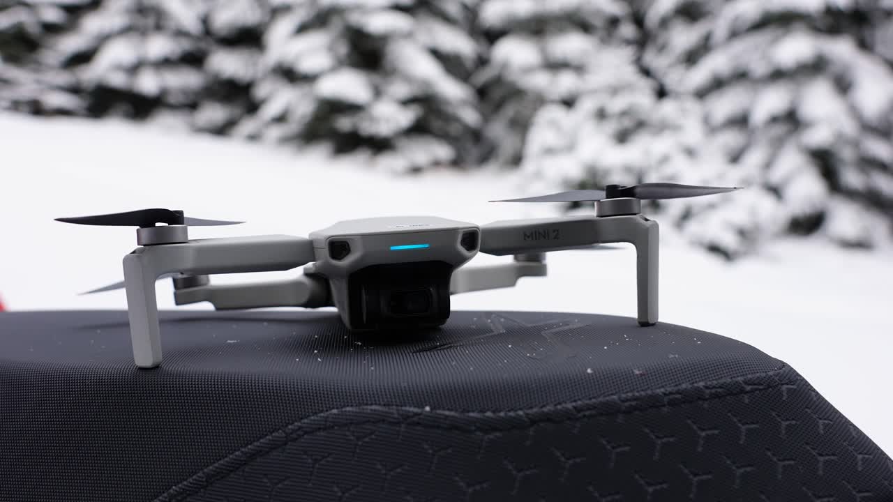 slowmo shot of a drone sitting on a snowmobile snowy