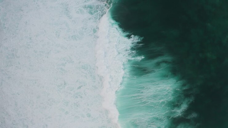 Powerful waves crash creating foam texture and swirly patterns