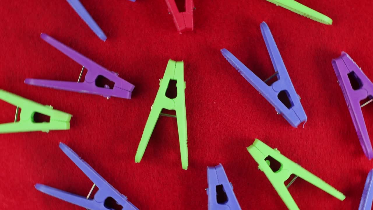 pinzas de ropa de colores en un fondo de textura roja, vista de arriba, primer plano, telón de fondo brillante.