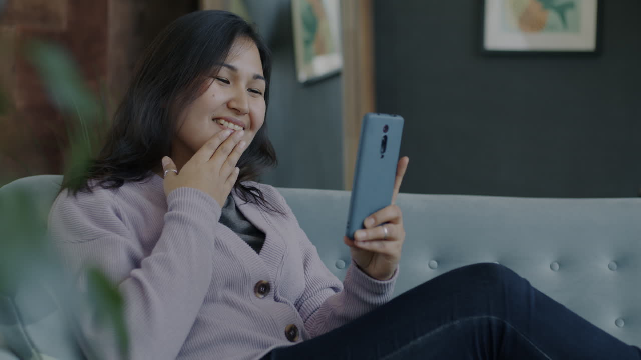 소파에서 스마트폰을 사용하는 여성