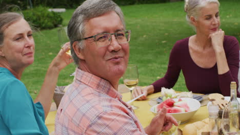 Animation-of-happy-caucasian-senior-man-eating-lunch-in-garden-with-friends