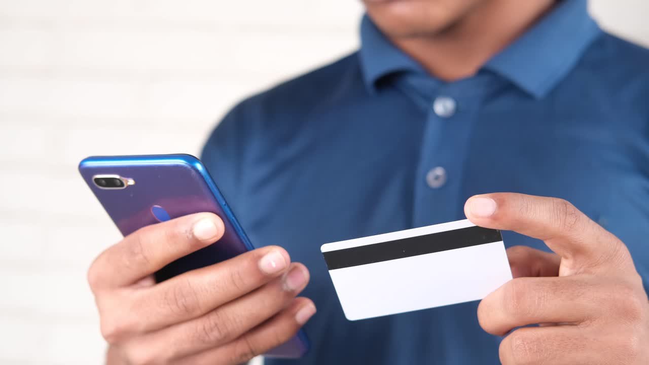 persona que utiliza un teléfono móvil y una tarjeta de crédito para el pago en línea