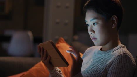 Schöne-Asiatische-Frau,-Die-Spät-In-Der-Nacht-Zu-Hause-Digitale-Tablet-Technologie-Nutzt