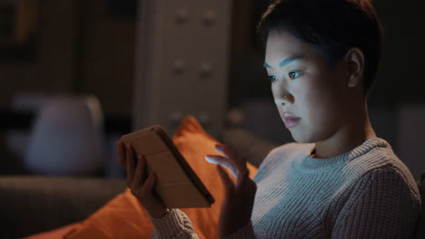 beautiful asian woman using digital tablet technology at home late night