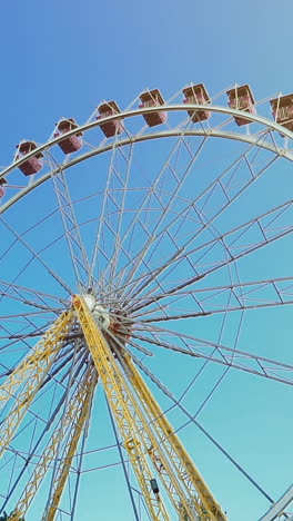 ferris wheel with colorful gondolas. blue sky and sunny day in amusement park vertical video