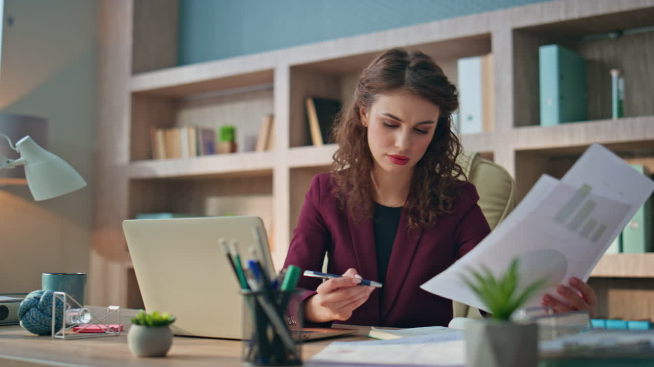 Concerned employee analyzing papers looking finance graph. Upset businesswoman