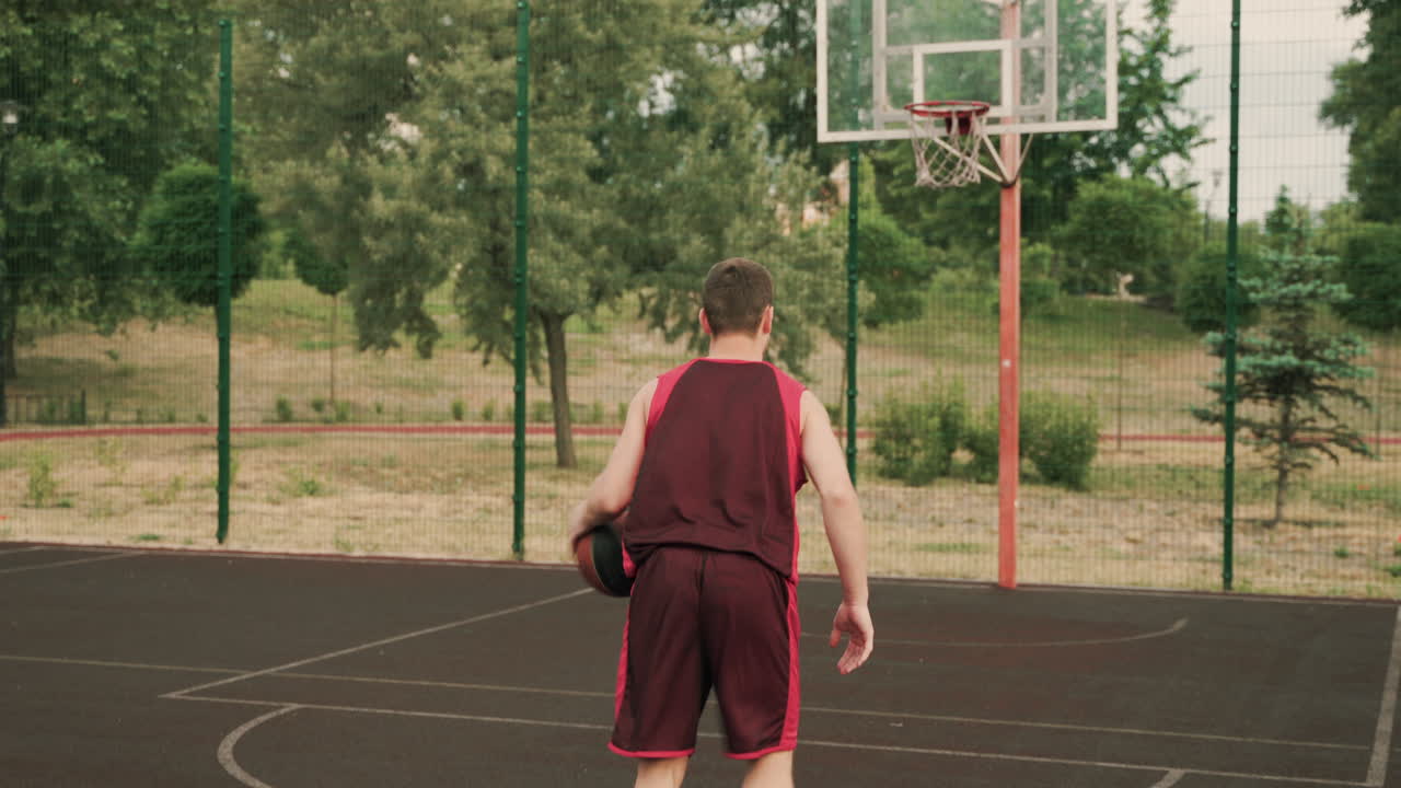 jugador de baloncesto masculino regateando y lanzando la pelota a la canasta durante su sesión de entrenamiento en una cancha de baloncesto al aire libre