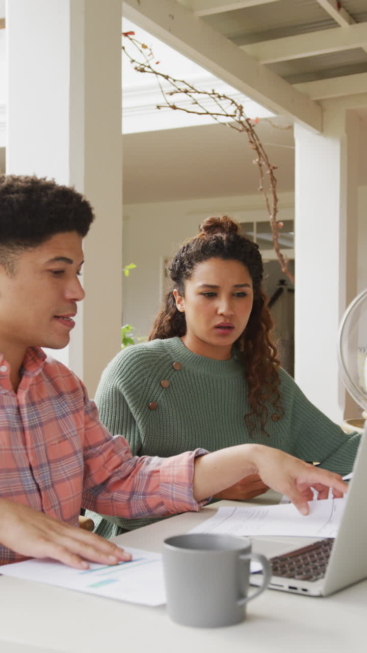 video vertical de una pareja biracial pagando cuentas