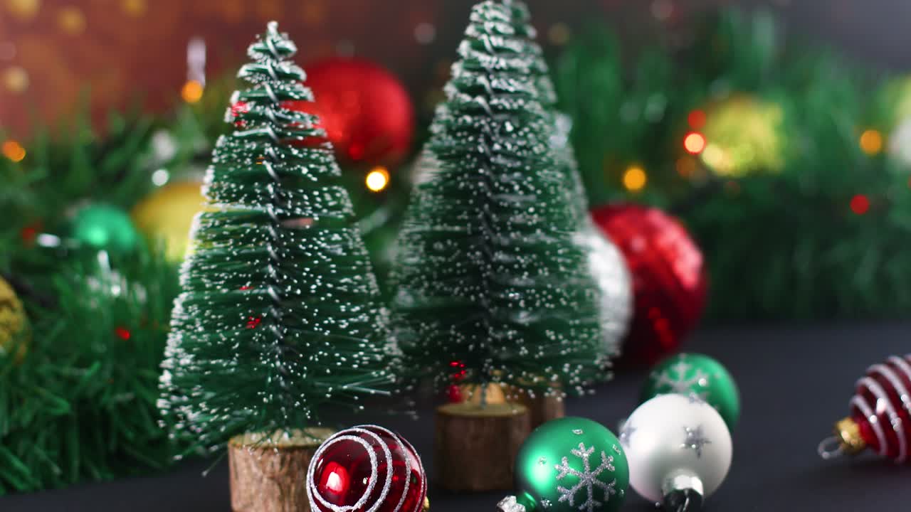 pequeños adornos de navidad y pinos de navidad con luces parpadeantes detrás.