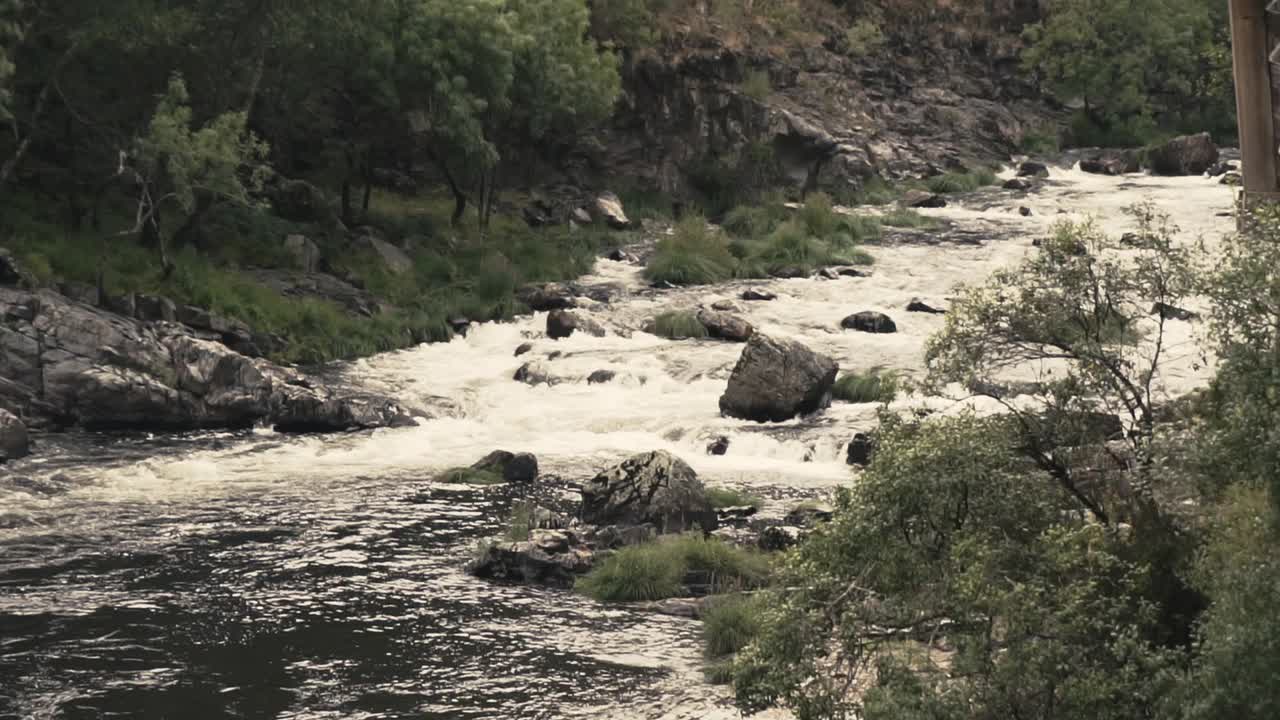 Calm river flowing down in slow motion between rocks and moss in forest mountains of Portugal