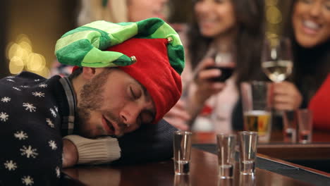 Man-Passed-Out-On-Bar-During-Christmas-Drinks-With-Friends