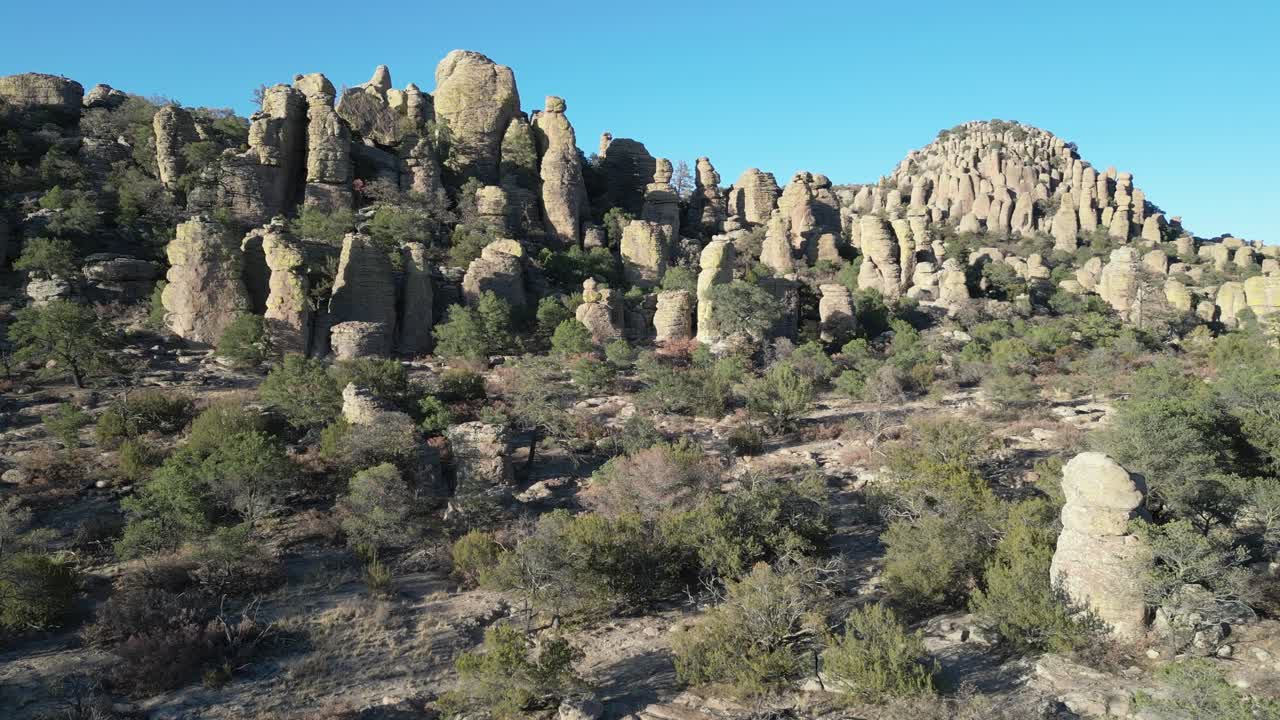 Rock spires and dry shrubs under clear sky in Valle de los Monjes, Creel, Chihuahua