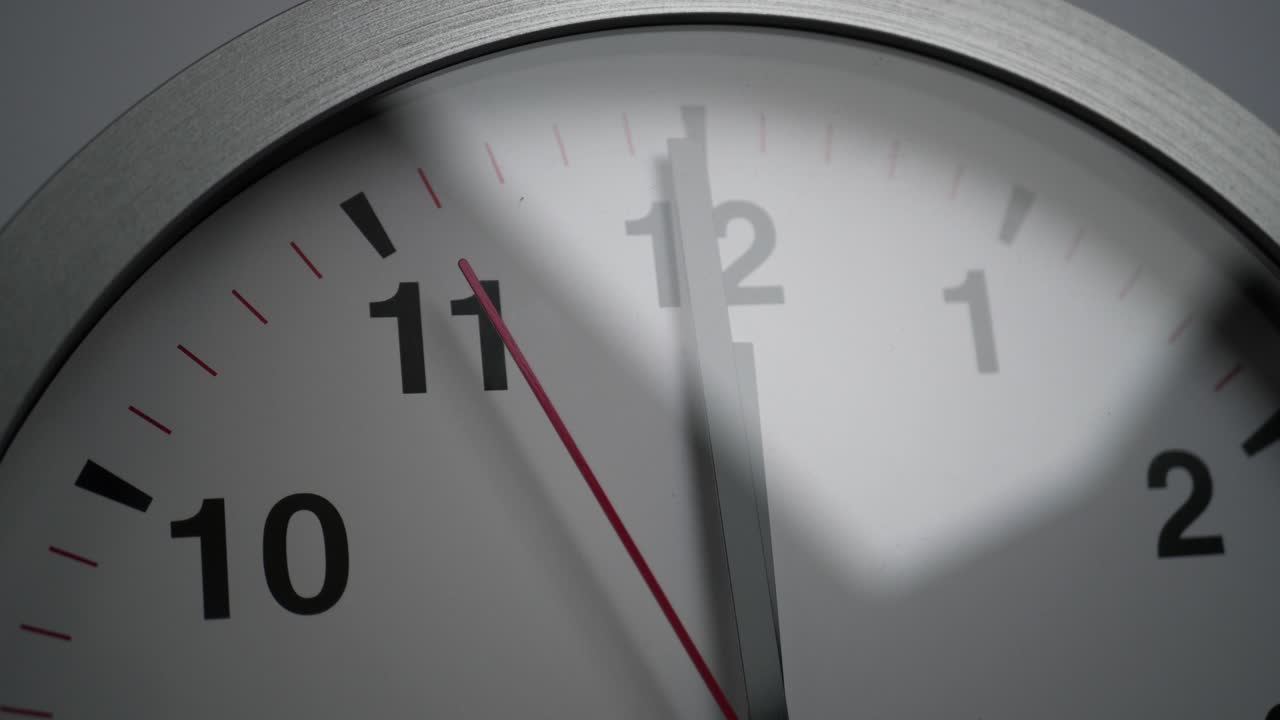 Close up of a white ticking clock on white background, pointing midnight, window reflection, time lapse
