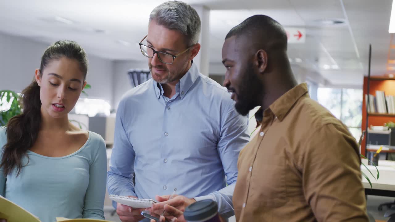 Diverse male and female business colleagues talking and holding documents