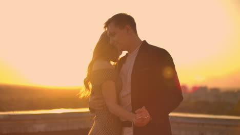 two lovers dance together on the roof at sunset in the sunlight. romantic dancing