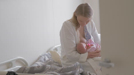 a woman breastfeeding her newborn baby in a maternity hospital room