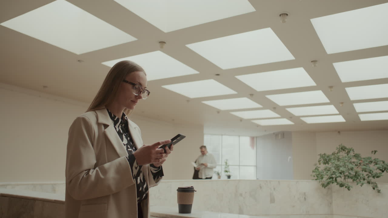Businesswoman Checking Smartphone during Workday in Modern Office Space