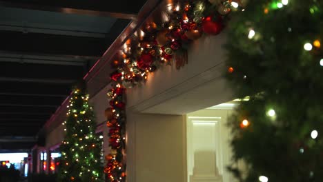 toma media de la corona de la bola de navidad colgando por encima de la puerta de un hotel de lujo hecho de bolas rojas y doradas, así como luces de hadas con una planta verde para foregorund