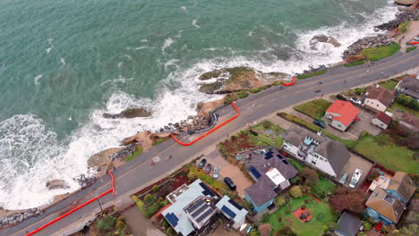 Downward-aerial-view-of-storm-hit-ocean-walkway,-ongoing-roadwork