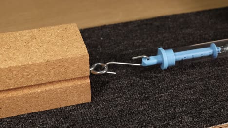 a hand uses a spring scale to measure the friction force of a wooden block on carpet