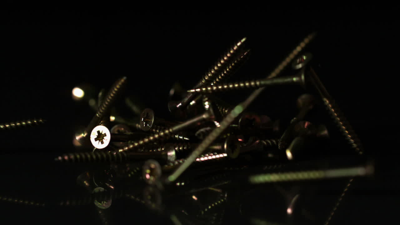 tornillos que caen sobre una superficie negra