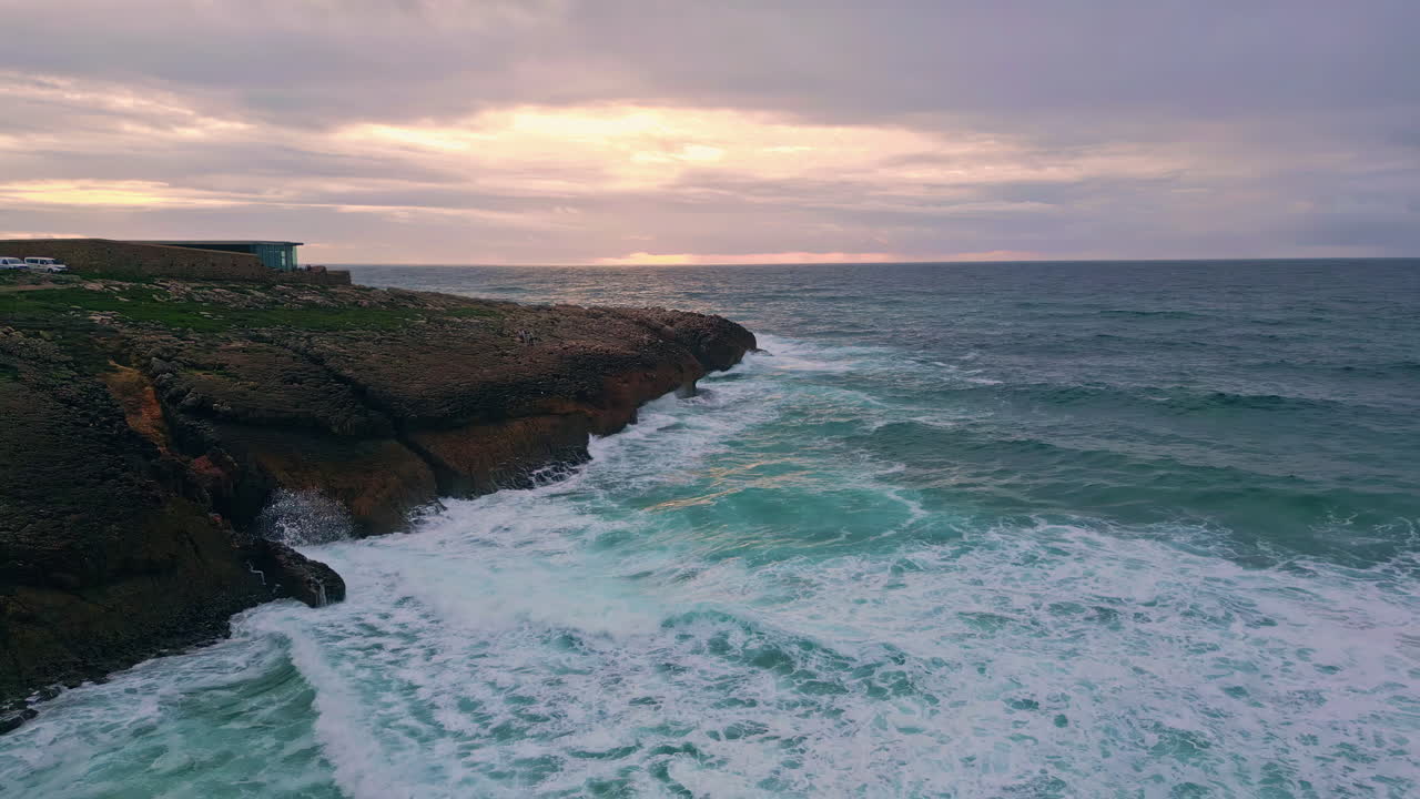Waves meeting rugged cliffs under sunset sky dramatic aerial view. Powerful sea
