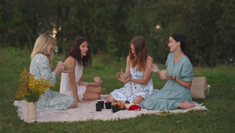 a group of young attractive women in nature in an open area sculpt from clay discuss the results of the lesson communicate share their impressions laugh rejoice at the results.