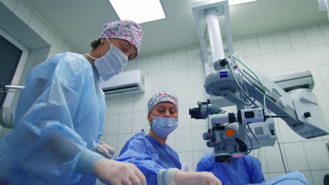 surgeon looking into the microscope. doctor with assistant doing eye surgery with modern microscope at the hospital