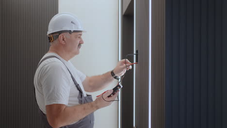 camera approaches electric checks the operation of the wall control unit of the lamps with the system of a modern house after installation and repair