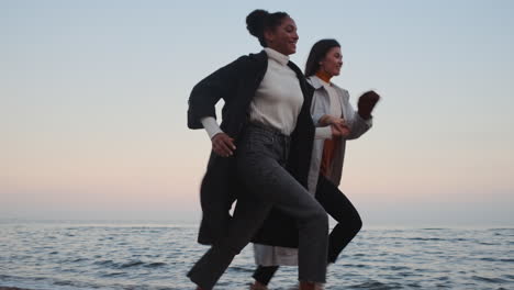 two stylish girls running by the sea.