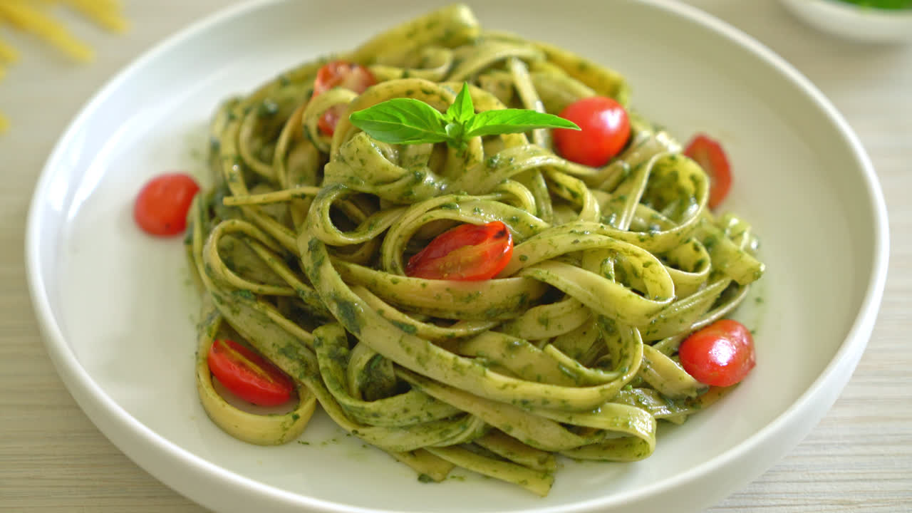 espaguetis fettuccine con salsa pesto y tomates - estilo de comida vegana y vegetariana