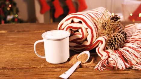 manta enrollada con cono de pino y taza de café