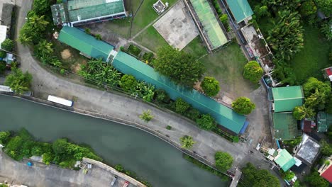 aerial top-down view of quaint town river and rural elementary school with lush greenery in virac, catanduanes