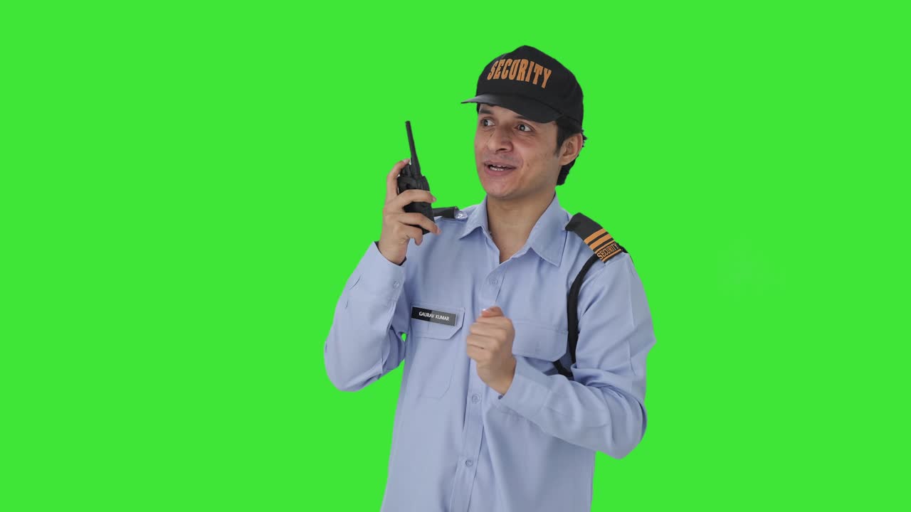 Guardia di sicurezza indiana felice che dà istruzioni via walkie-talkie, schermo verde
