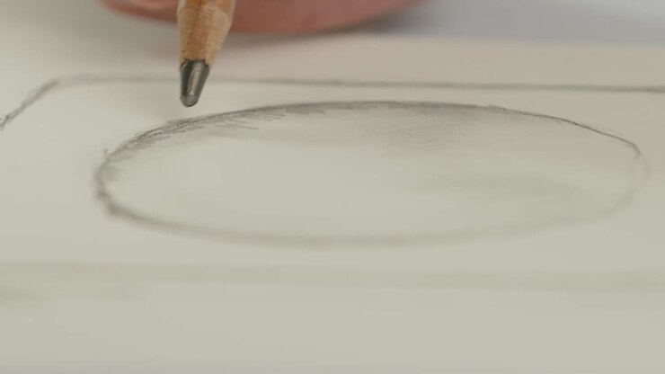 The designer draws a contour and a shadow of a perfume bottle with a pencil - the packaging design process. Close-up shot.