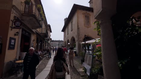 charming cobblestone street scene in orta san giulio, italy, showcasing rustic arches, historic architecture, and people enjoying a leisurely stroll in this quaint italian village