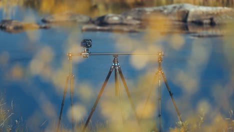 a professional camera on the slider rig stands on the bank of the river