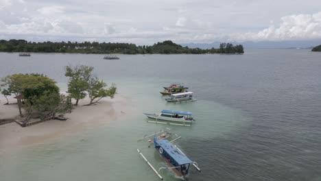 aerial orbit: outrigger tour boats anchor off sand beach, lombok