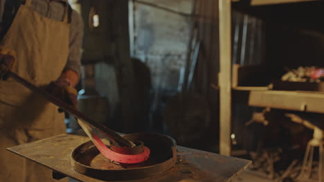 blacksmith heating steel workpiece in forge and bending it into spiral