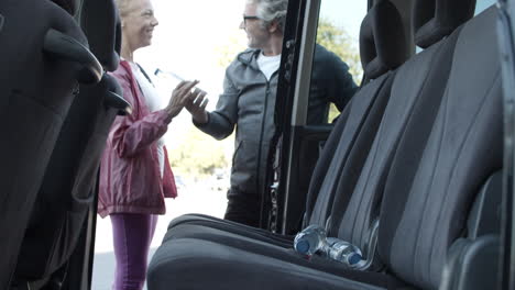 two people taking bottle of water from car before training