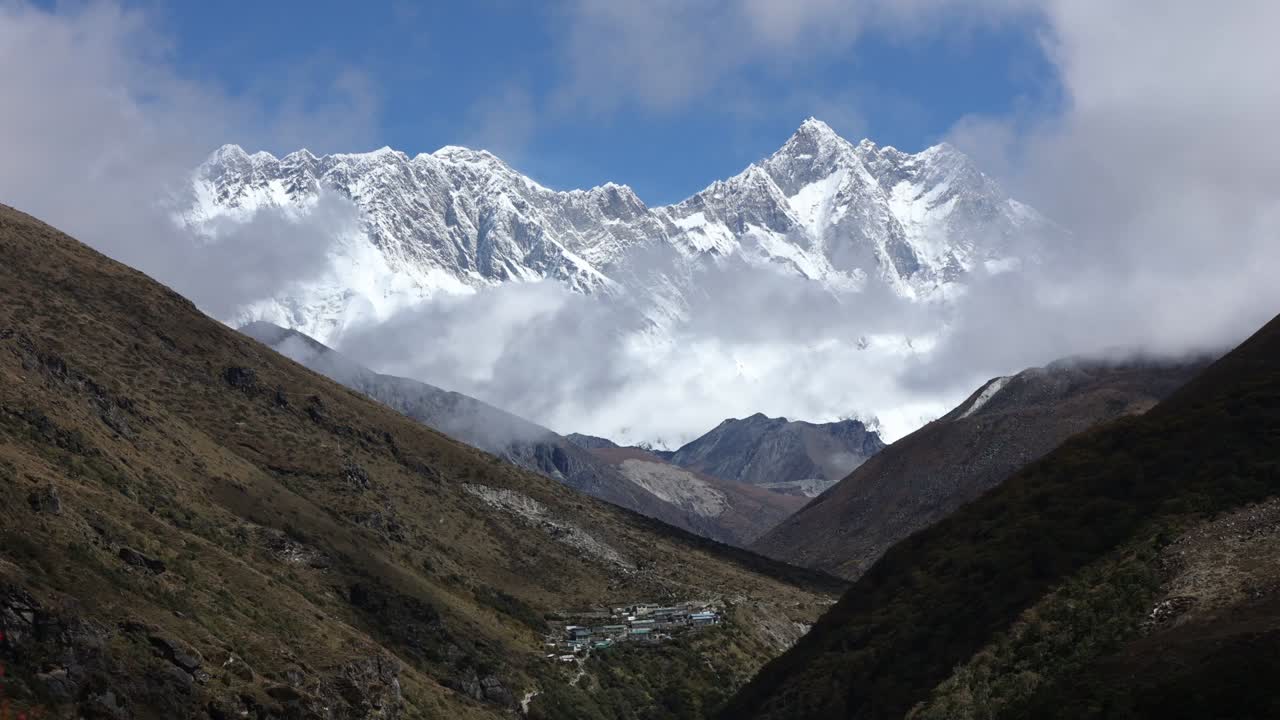 Beautiful view of snow-covered Annapurna peaks seen from Annapurna Base Camp in Kaski District, Nepal, with clouds drifting over rugged hills and a serene Himalayan valley below