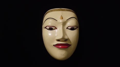 traditional wood carved topeng mask of balinese hinduism theater, bali indonesia closeup, black background